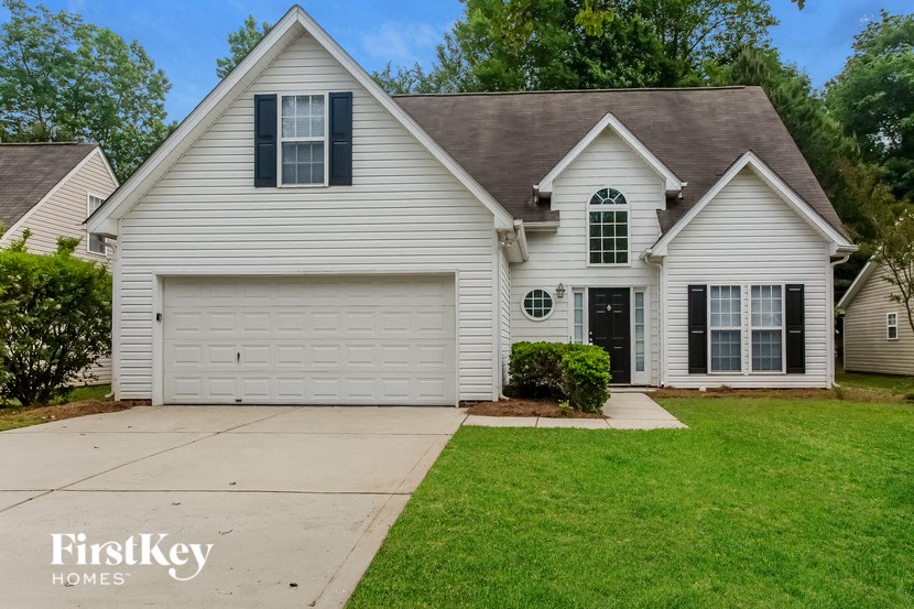 A white house with a brown roof and a garage door.
