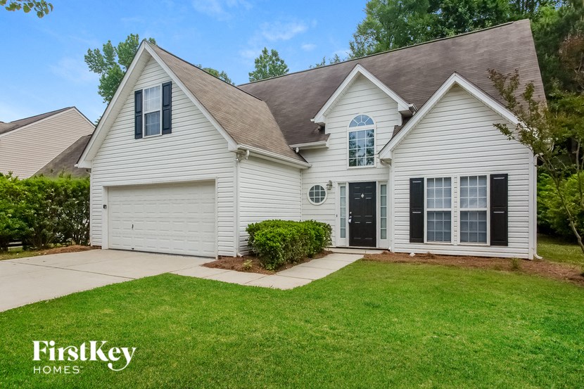 A white house with a brown roof and a garage door.