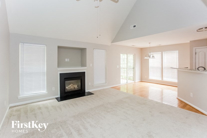 A spacious living room with a fireplace and a carpet on the floor.