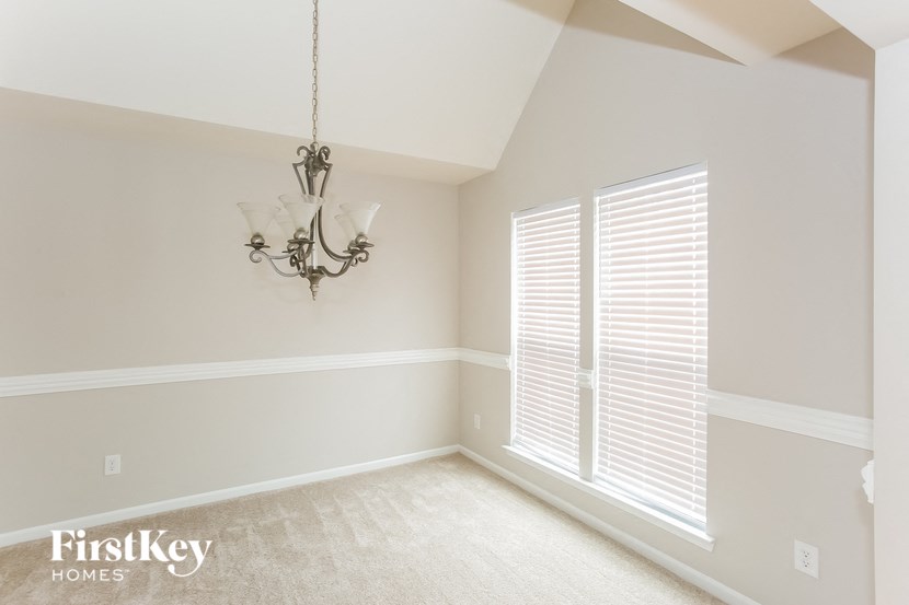 A room with a chandelier and a window with blinds.