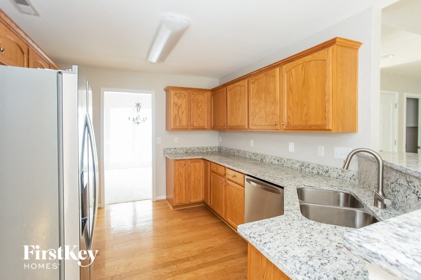 A kitchen with a refrigerator, sink and cabinets.