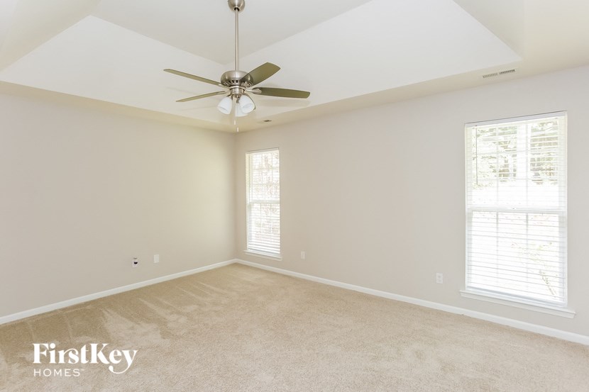A spacious room with a ceiling fan and a window with blinds.