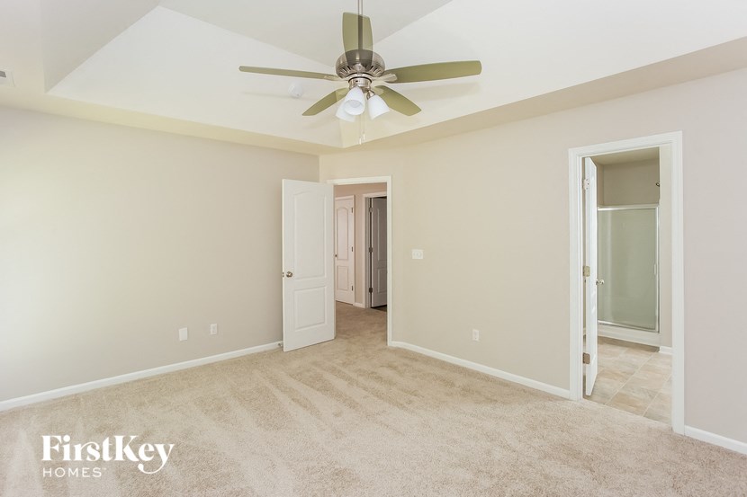 A spacious room with a ceiling fan and a doorway leading to another room.