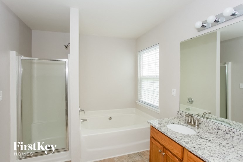 A white bathroom with a tub, sink and mirror.
