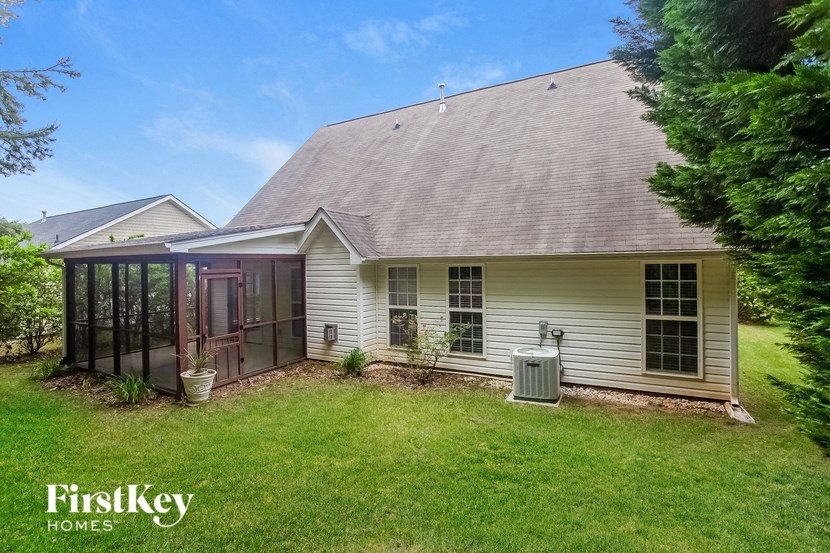 A house with a grey roof and a white wall with a window and a door.