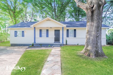 a white house with blue shutters and a tree