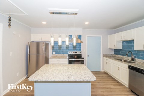 a kitchen with white cabinets and granite counter tops and stainless steel appliances