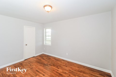 a bedroom with wood flooring and white walls and a white door