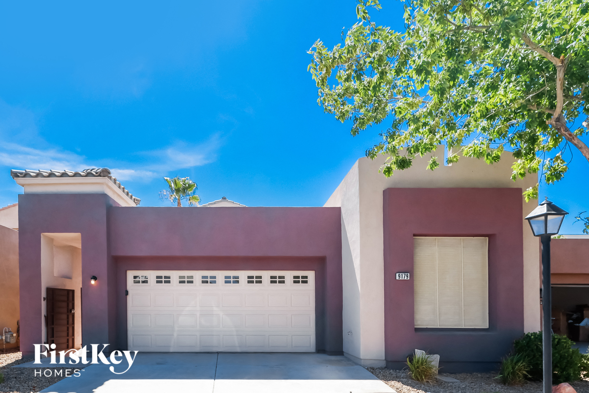a pink house with a garage door and a tree