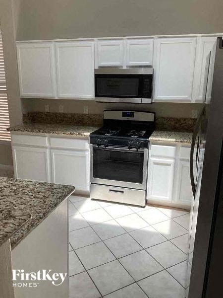 a kitchen with a stove and microwave and white cabinets