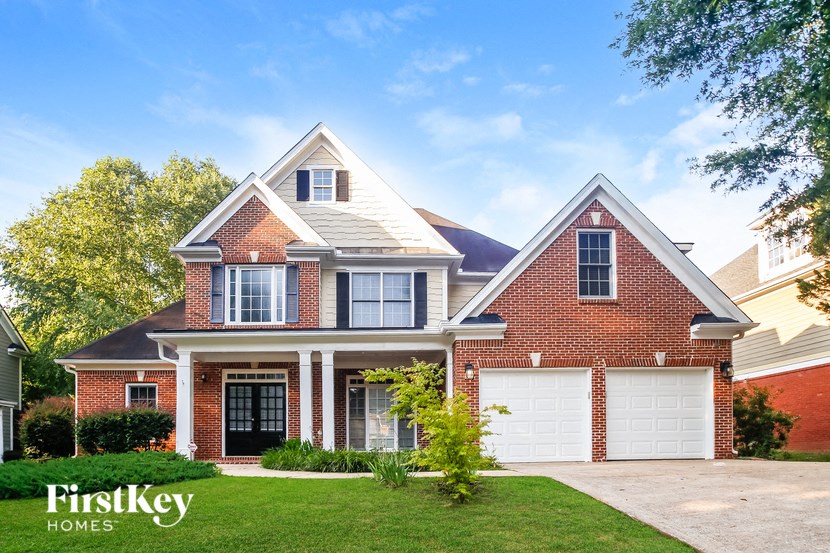 A brick house with a black front door and two garages.