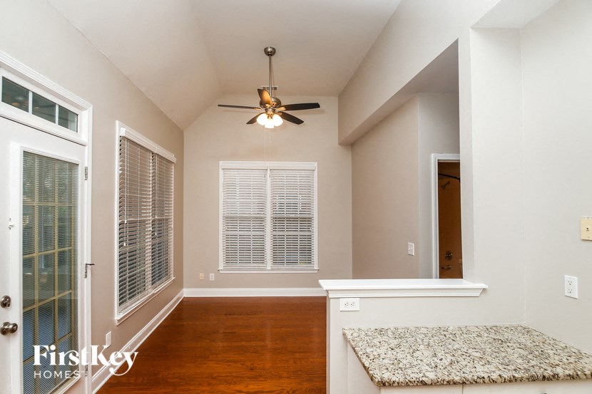 A room with a ceiling fan and a rug on the floor.
