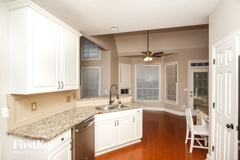 A kitchen with white cabinets and a granite countertop.