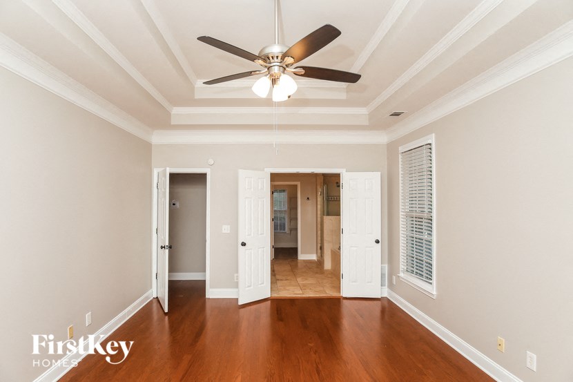 A spacious room with a ceiling fan and wooden floors.