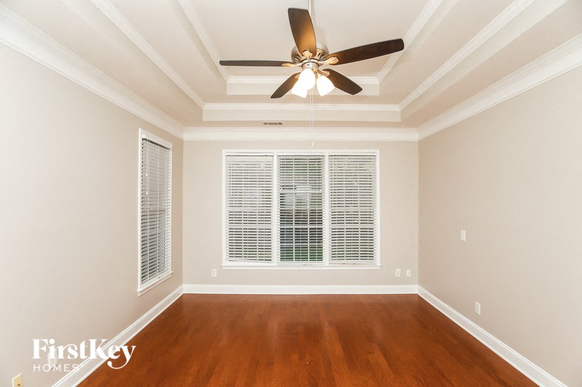 A room with a ceiling fan and wooden floors.