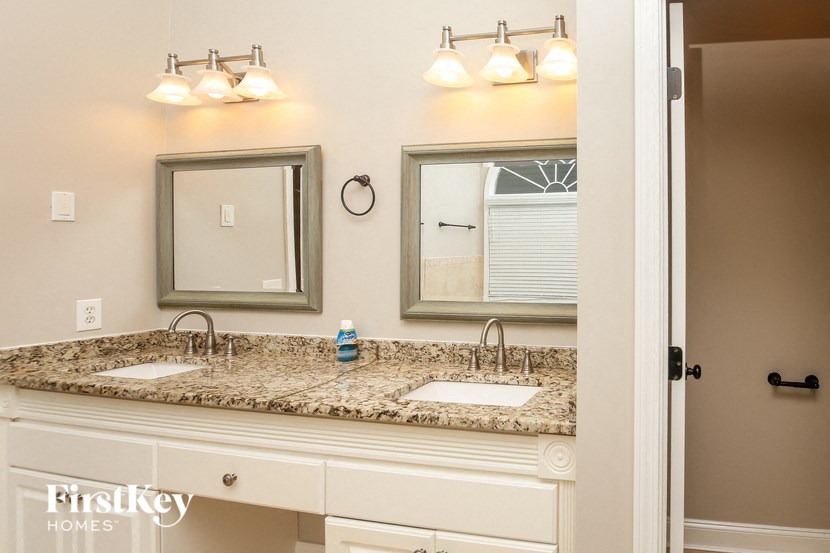 A bathroom with a granite countertop and a mirror above it.