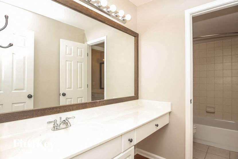 A white bathroom with a mirror and a bathtub.
