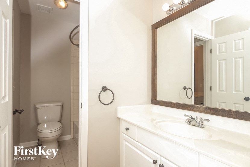 A bathroom with a toilet, sink and mirror.