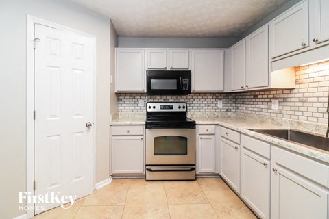 A kitchen with white cabinets and a black microwave above the stove.