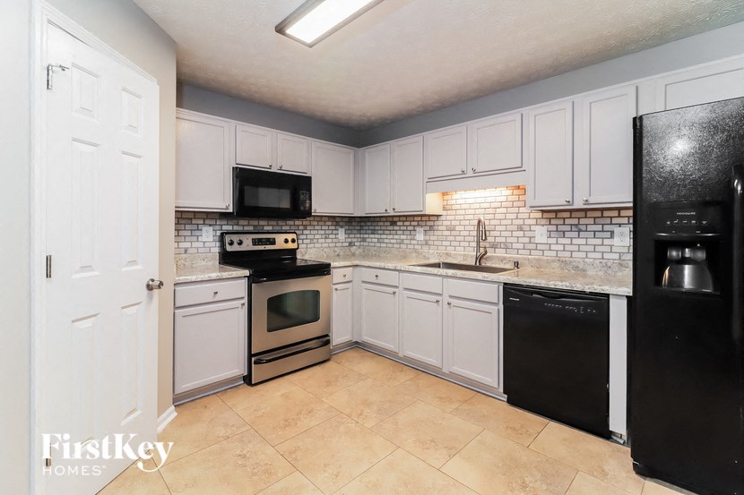 A kitchen with a black fridge and white cabinets.