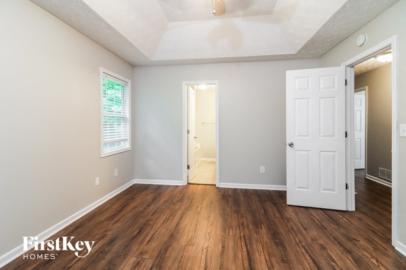 A room with wooden floors and white walls, with a door in the center.
