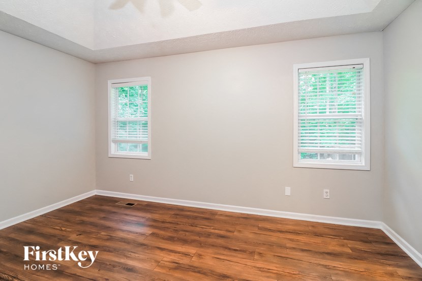 A room with wooden floors and two windows.
