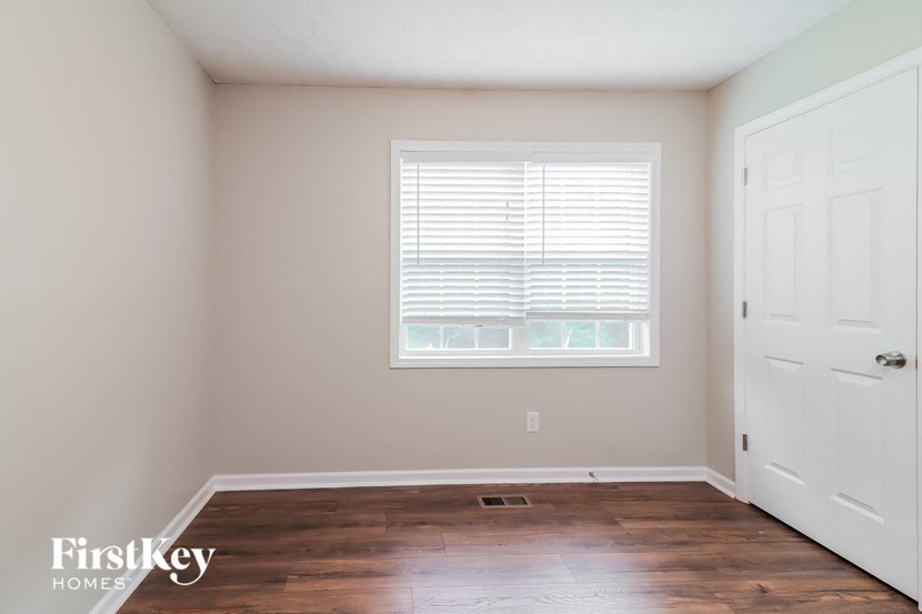 A room with a white door and a window with blinds.