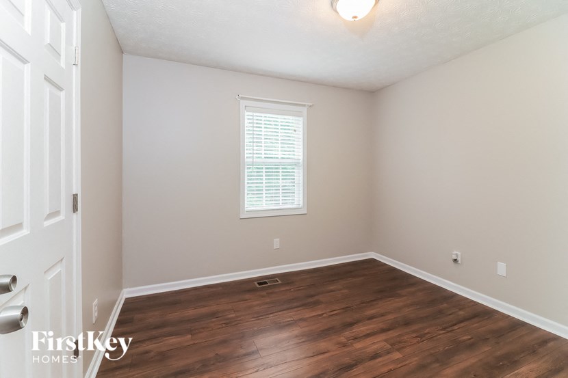 A room with a wooden floor and a window with blinds.