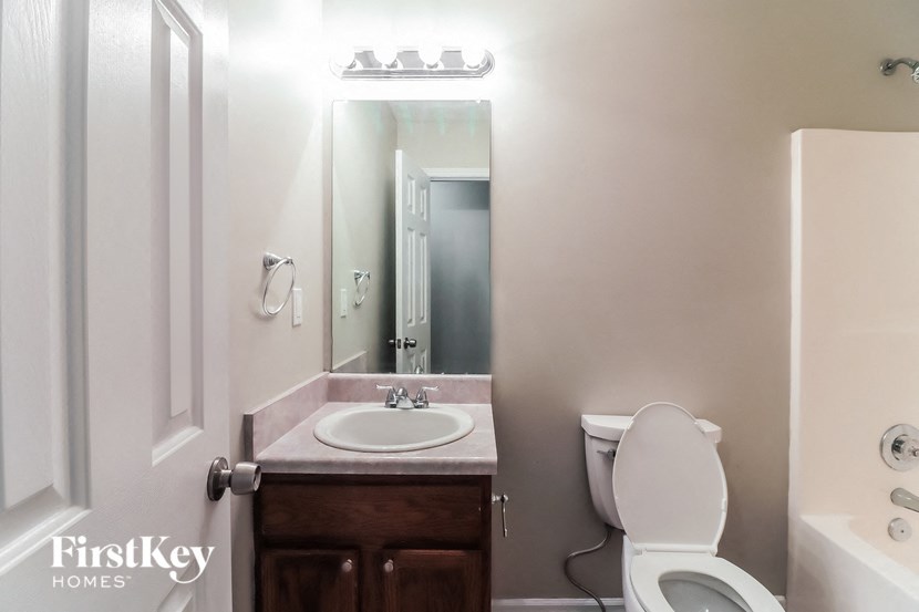 A bathroom with a toilet, sink, and mirror.