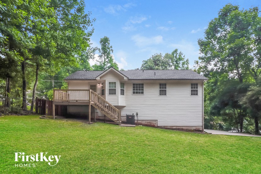 A house with a deck and a tree in front of it.