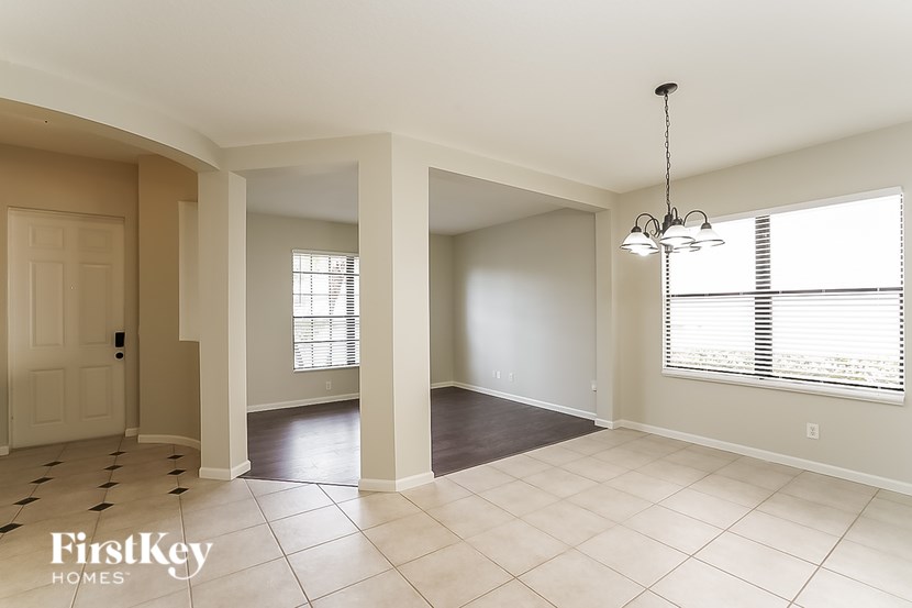A spacious room with a tiled floor and a chandelier hanging from the ceiling.