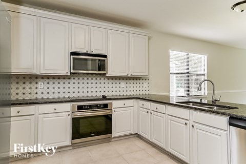 A kitchen with white cabinets and a black countertop.