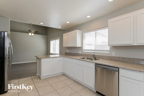 A kitchen with white cabinets and a granite countertop.