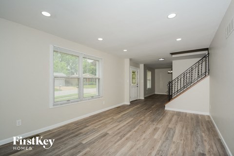 the living room and entryway of a new home with white walls and wood floors
