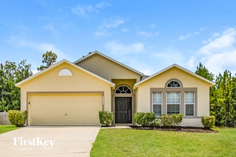 a yellow house with a garage door and a lawn
