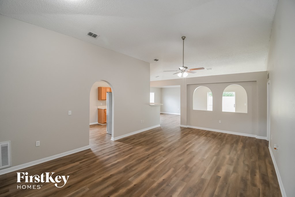 the living room and dining room with hardwood floors and a ceiling fan