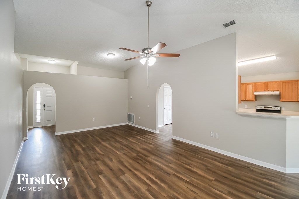 an empty living room with hardwood flooring and a ceiling fan