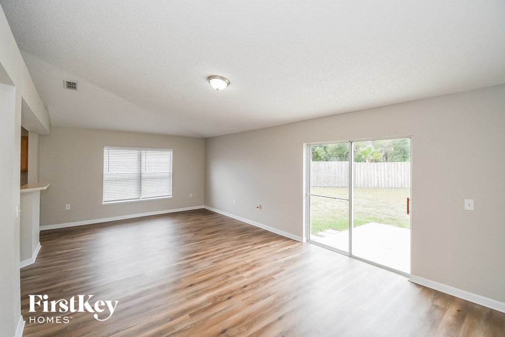an empty living room with a sliding glass door to a yard