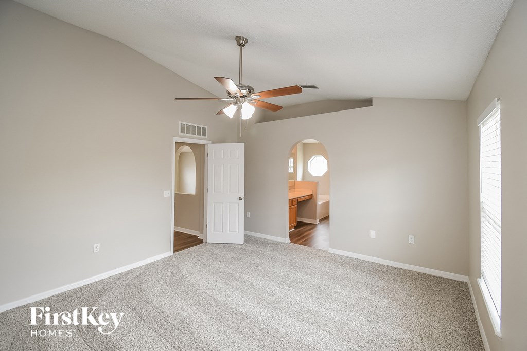 a spacious living room with carpet and a ceiling fan