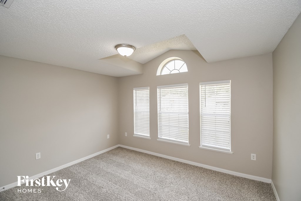 the spacious living room has a large window and carpeted flooring