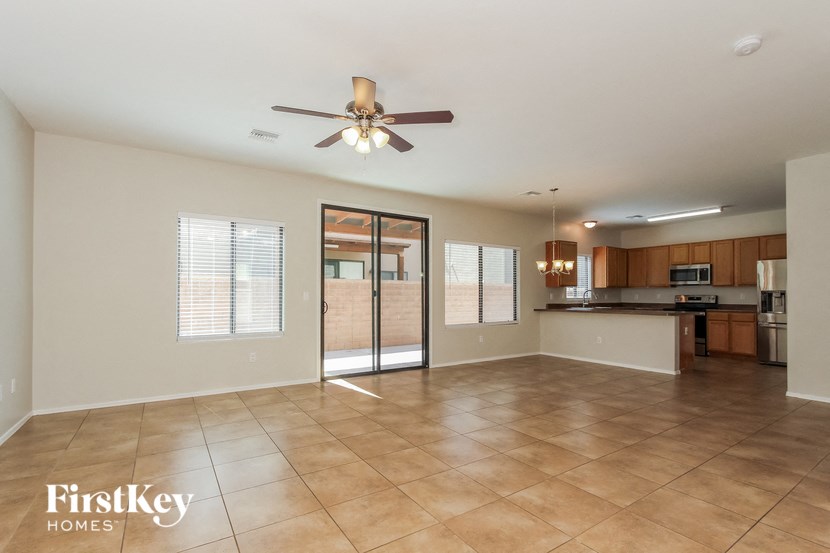 an empty living room with a ceiling fan and a kitchen