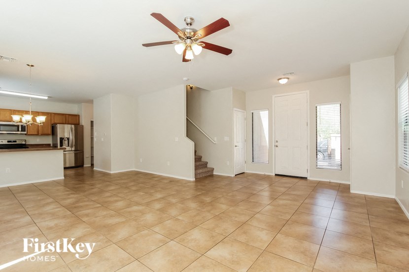 an empty living room with a ceiling fan and a kitchen