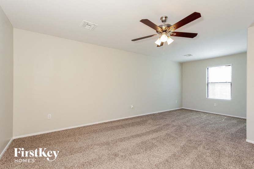 the spacious living room with ceiling fan and carpeting