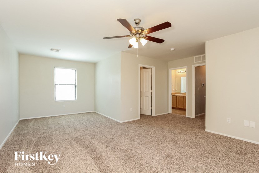 a spacious living room with carpet and a ceiling fan