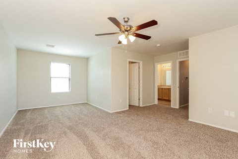 a spacious living room with carpet and a ceiling fan