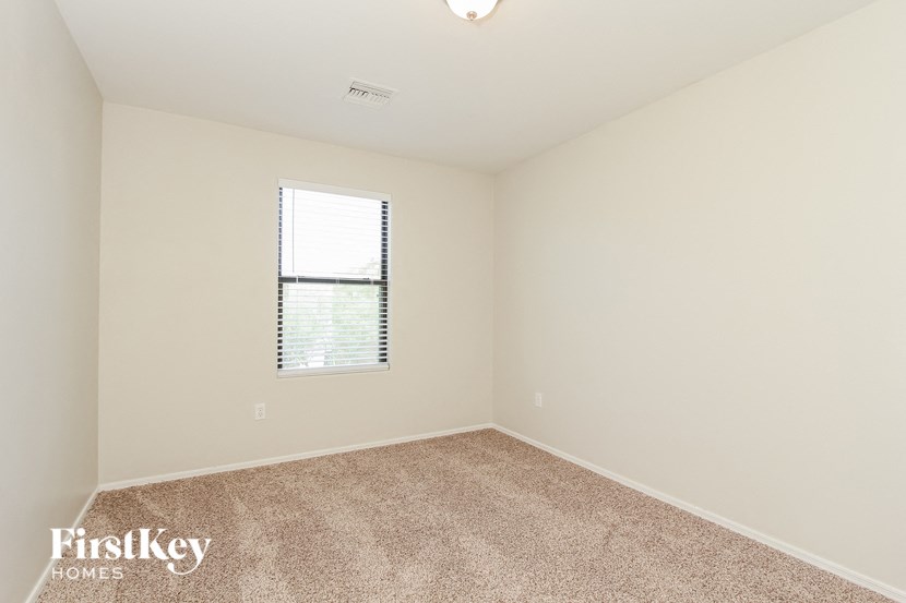 a spacious room with carpet and a window