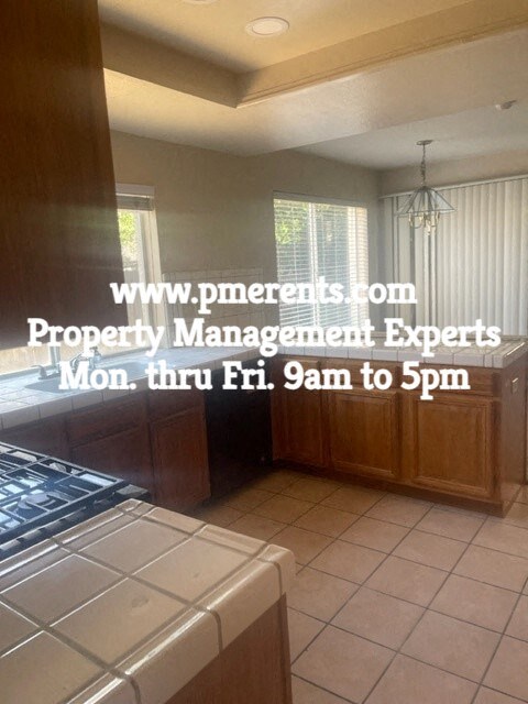 A kitchen with a stove top oven and a website address for property management experts.