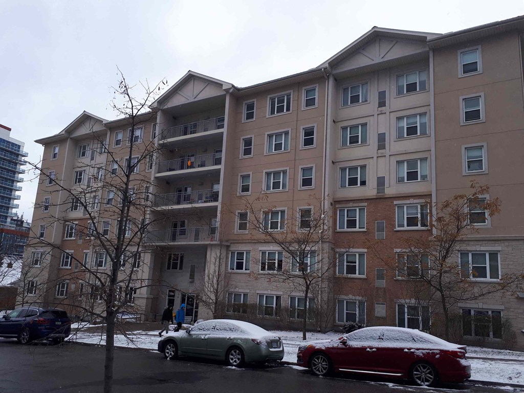 an apartment building with cars parked outside in the snow