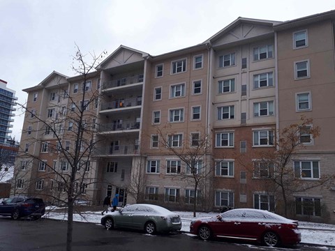 an apartment building with cars parked outside in the snow