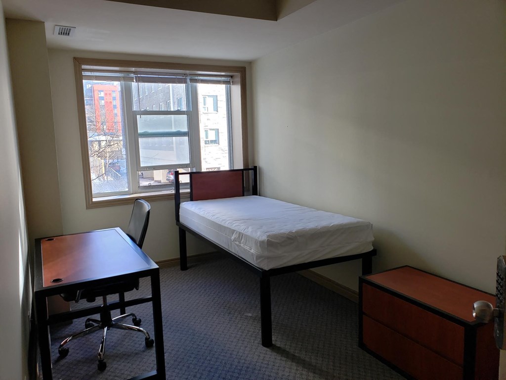 a bedroom with a bed and a desk and a window